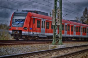 Zu sehen ist eine rot-graue S-Bahn auf einer mehrgleisigen Bahnstrecke
