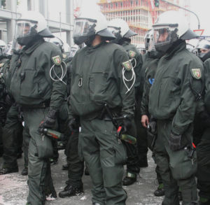 Mehrere Polizisten in massiver Schutzausrüstung und mit Pfefferspray bewaffnet