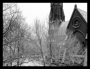 Verschneite Kirche hinter Bäumen