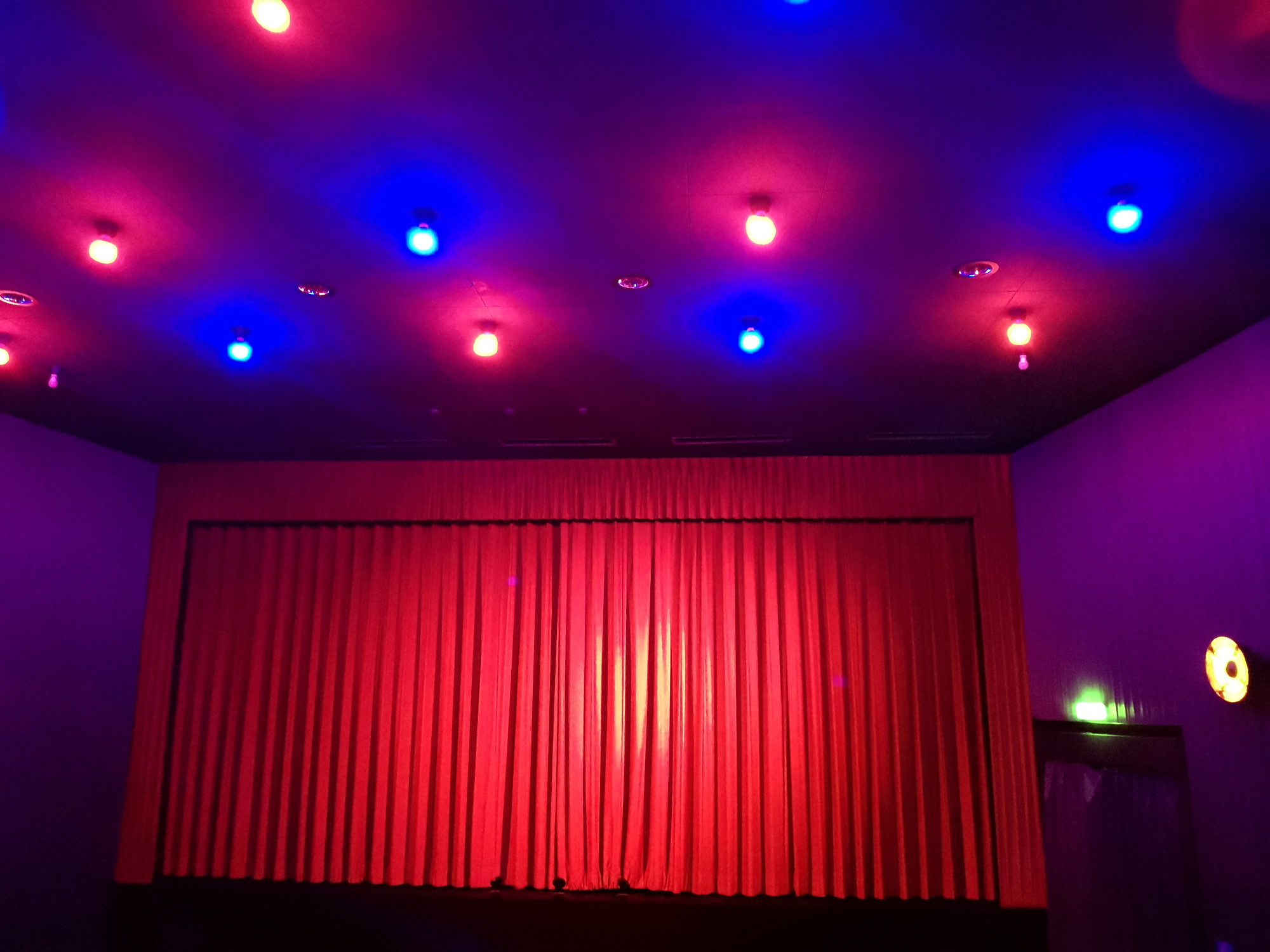 Kinosaal. Zu sehen das CinePlanet 5 in Bad Segeberg, Saal CP 3 am 03. Oktober beim Film Wochenendrebellen. Relativ grelle rote und blaue Deckenbeleuchtung.